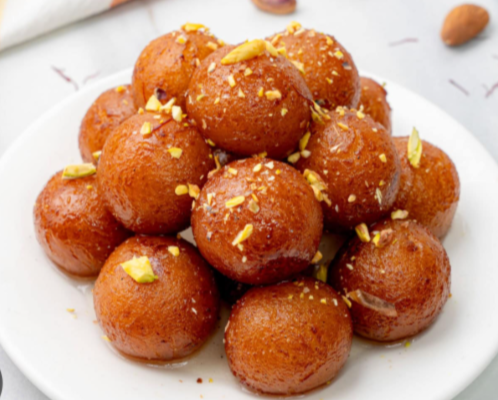 A plate of soft and juicy Golap Jamun soaked in sugar syrup, garnished with chopped pistachios.