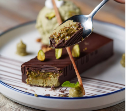 Delicious homemade Dubai chocolate bar topped with crushed pistachios and edible gold flakes for a luxurious touch.